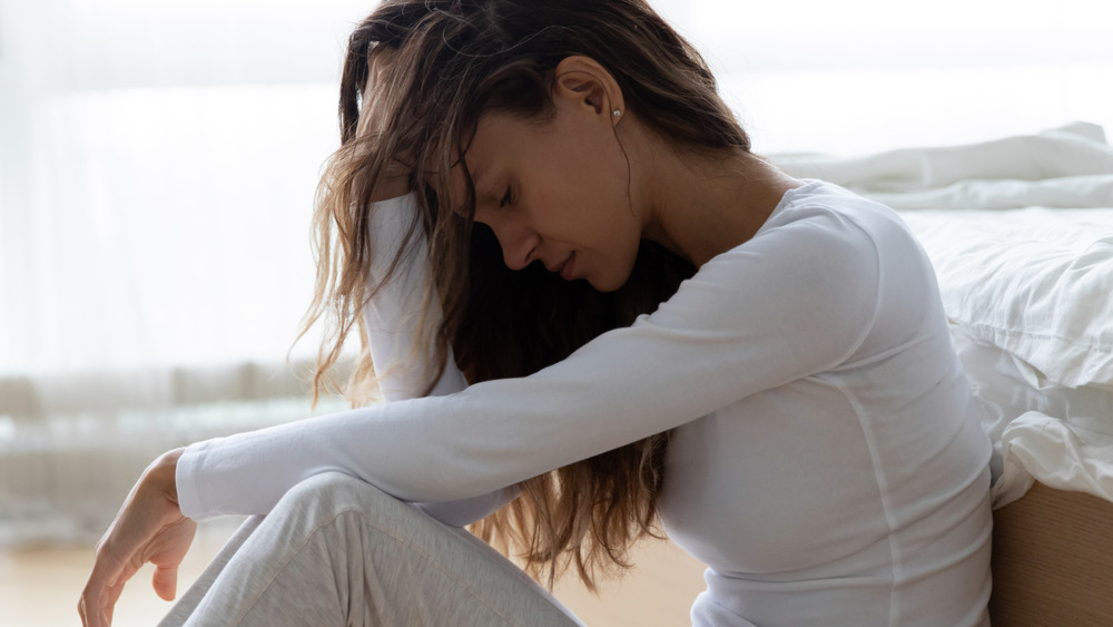 Worried woman sitting beside bed