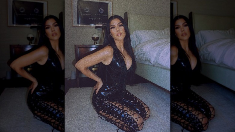 Kourtney Kardashian posing in a leather, tie-up jumpsuit