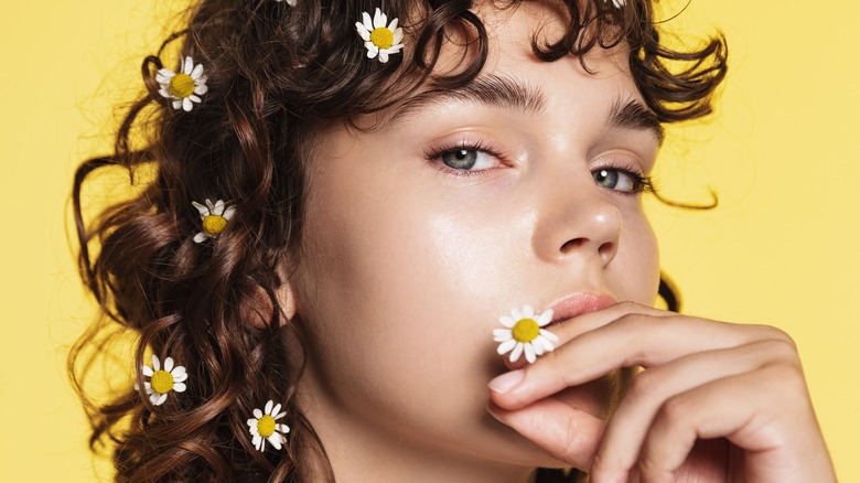 curly-haired woman with chamomile flowers in hr hair