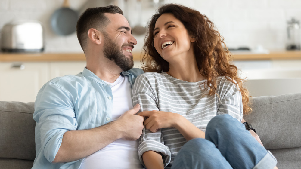 Couple laughs together on the couch