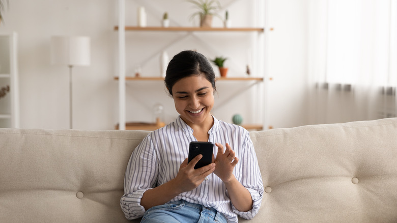 A woman smiles at her phone