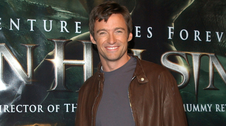Hugh Jackman smiling in front of 'Van Helsing' poster