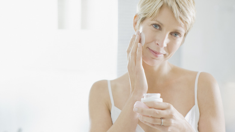 A woman applying lotion to her face 