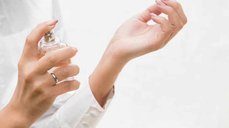 woman spraying perfume on her wrist