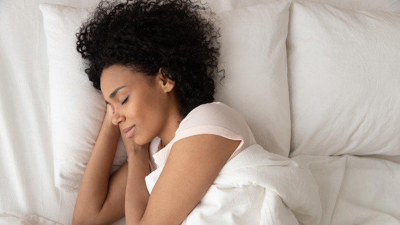 Woman sleeping on white pillow under white sheets
