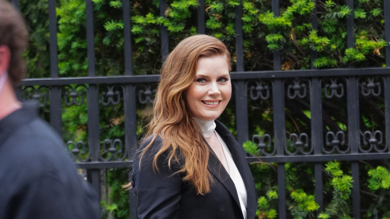 Amy Adams in front of an iron fence smiling