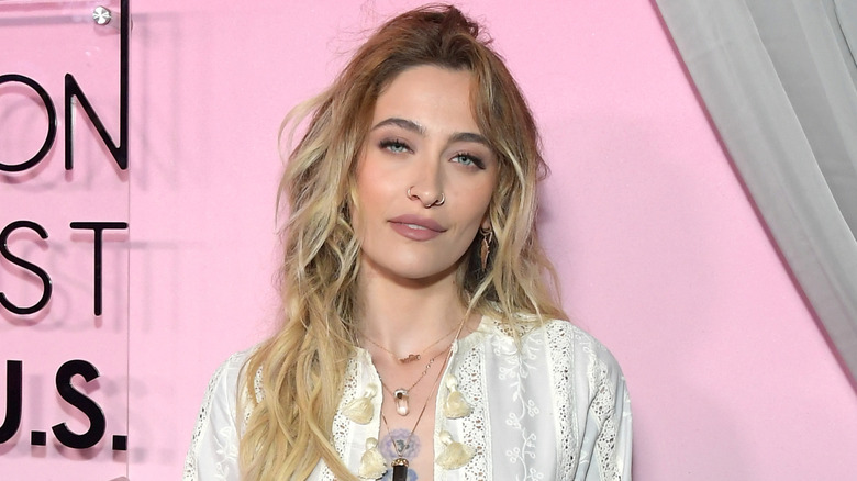 Paris Jackson posing at an event in a white lace top