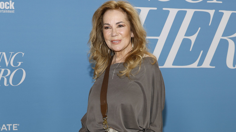 Kathie Lee Gifford smiling and posing in a gray top.