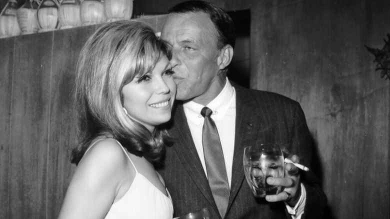 Pop singer Frank Sinatra enjoys a cocktail at an event with his daughter singer Nancy Sinatra in circa 1967.