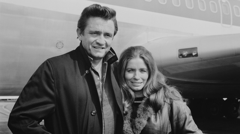 Johnny Cash and June Carter pose next to a plane