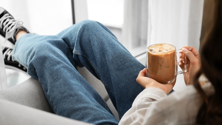 woman sitting holding iced coffee