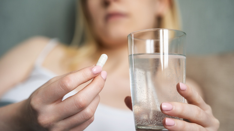 woman holding pill and water