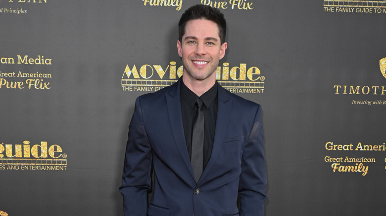 Dylan Geyer in a navy suit with a black tie and shirt at the 2026 Movie Guide Awards