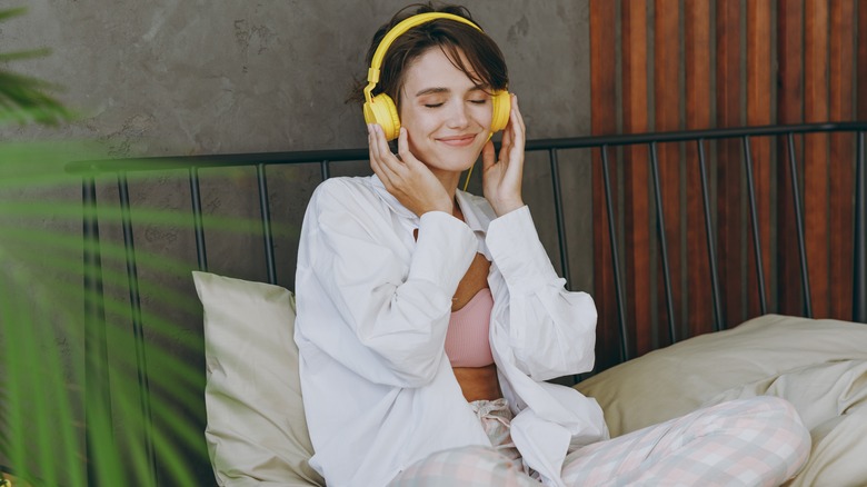 woman with headphones in bed