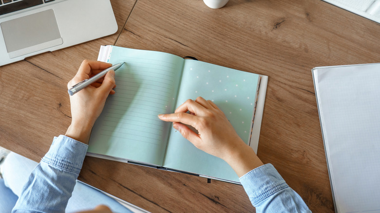 Writing in a journal on a desk 