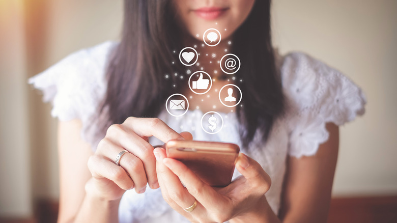 Young woman holding a phone receiving social media notifications