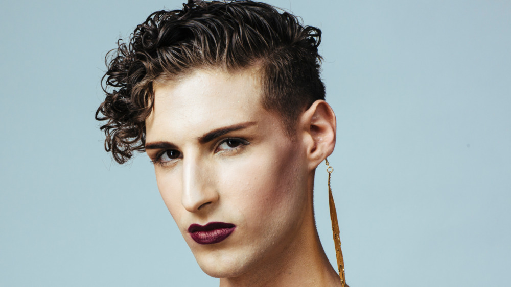 Young man wearing eyeliner, mascara, and lipstick