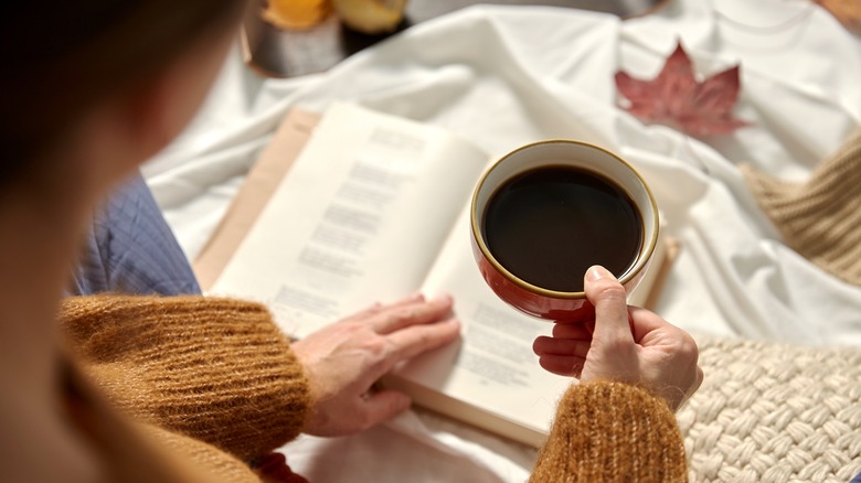 woman holding mug over poetry book
