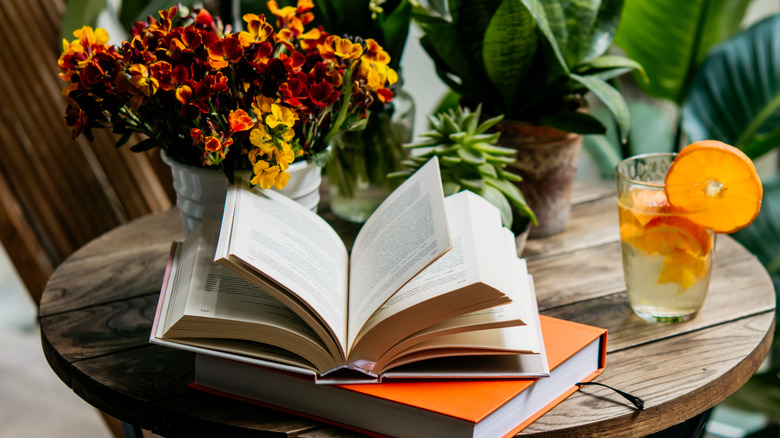 Books on a table surrounded by plants and flowers