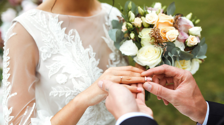 husband putting wedding ring on wife