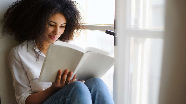 woman reading a book in a window