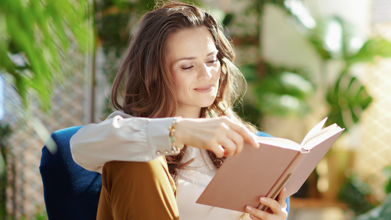 Woman reading book around plants