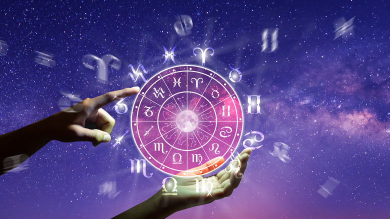 Astrology wheel with hands over the sky