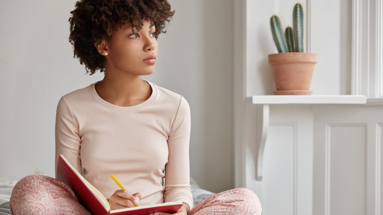 woman sitting in bed and journaling 