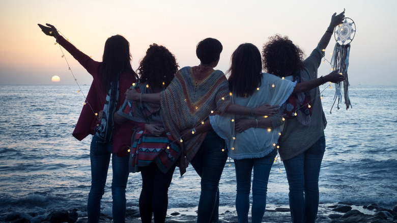 five friends hug each other on beach