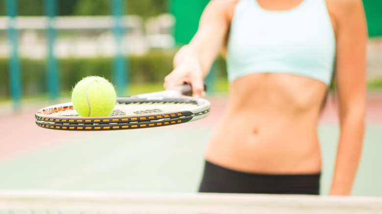 Woman holding a tennis rack and ball