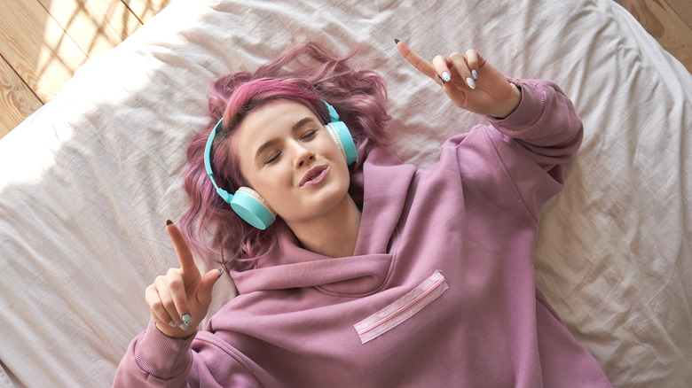 Woman lying on bed with headphones