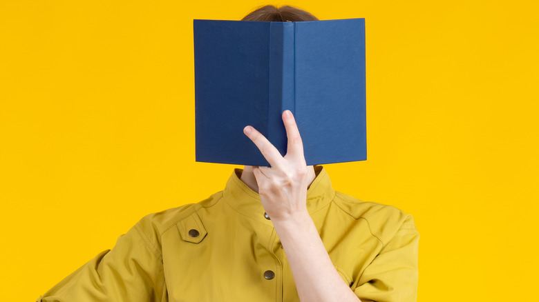Woman holding a book in front of her face