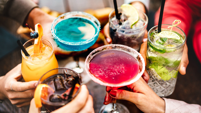 People cheers with colorful drinks