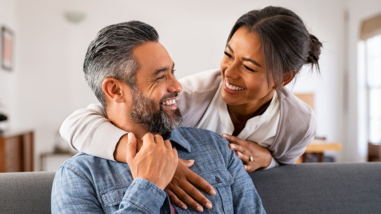 woman hugging man from behind and smiling at each other