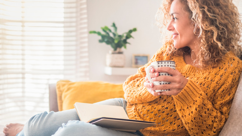 Woman holding a mug and open book 