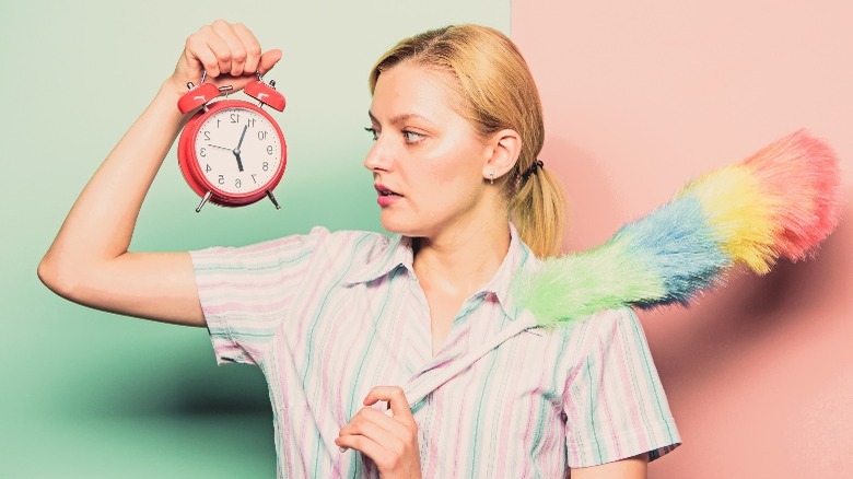 A woman holding a clock and a duster