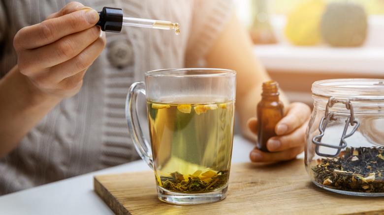 Woman putting CBD in a cup of tea