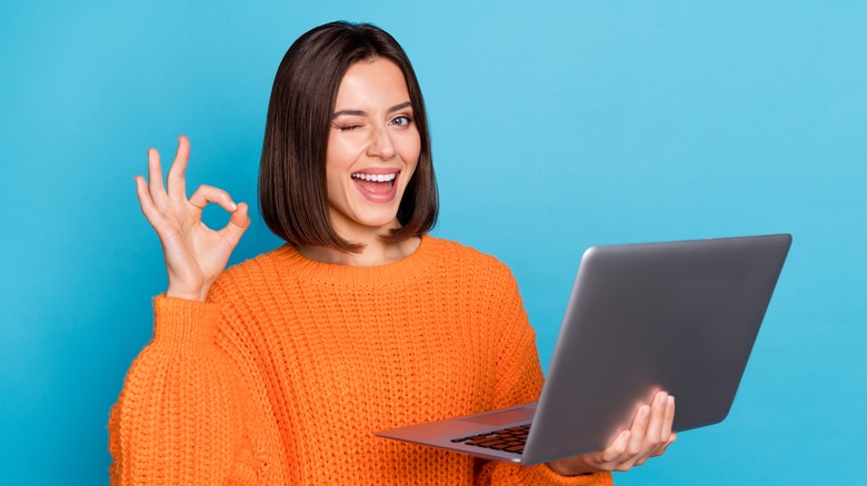 woman saying "a-okay" with a laptop in hand