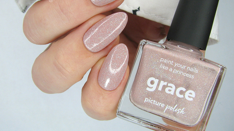 nails with a sparkly light pink polish with a bottle of nail polish