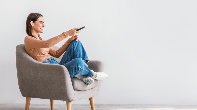 girl watching tv with a remote in hand