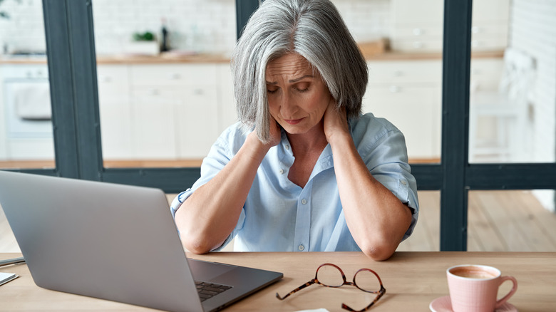 Stressed woman sitting at a desk with her hands on top of her head