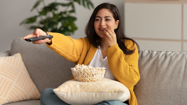 Women holding remote and eating popcorn