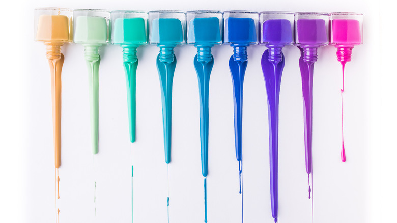 rainbow of nail polish bottles with polish spilling down