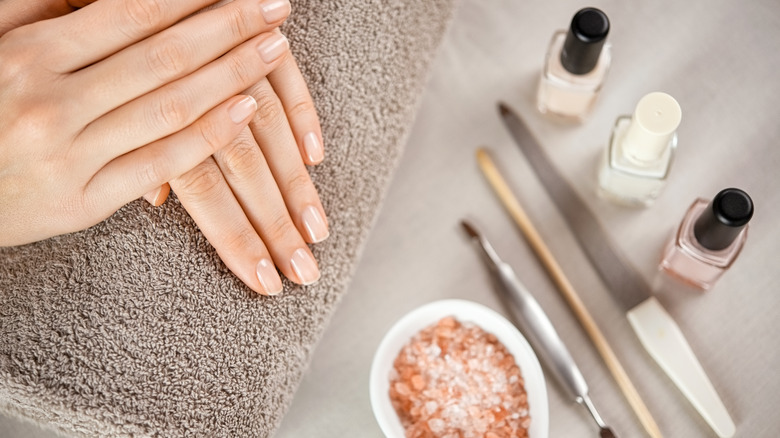 Hands next to nail polish and tools