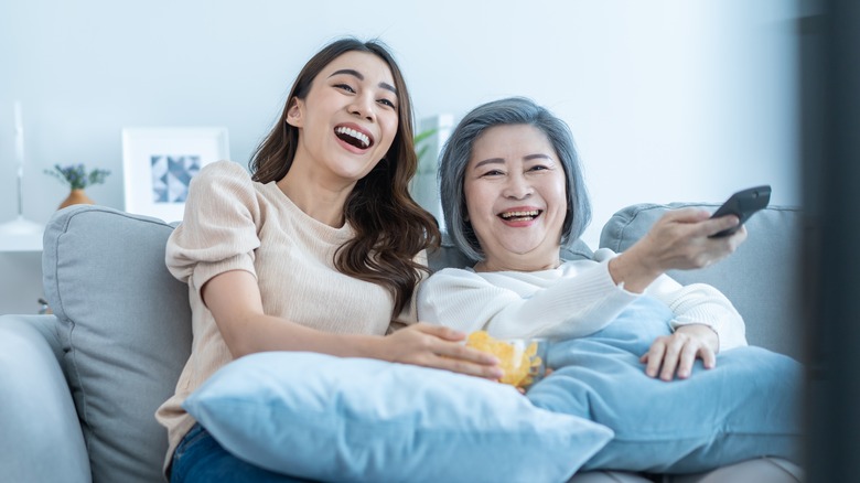 Young and older woman smiling at TV
