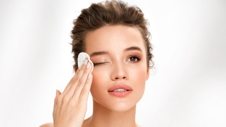 Woman using cotton round to remove makeup