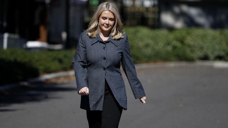 Karoline Leavitt pictured outside wearing a large dark grey pinstriped blazer and black pants