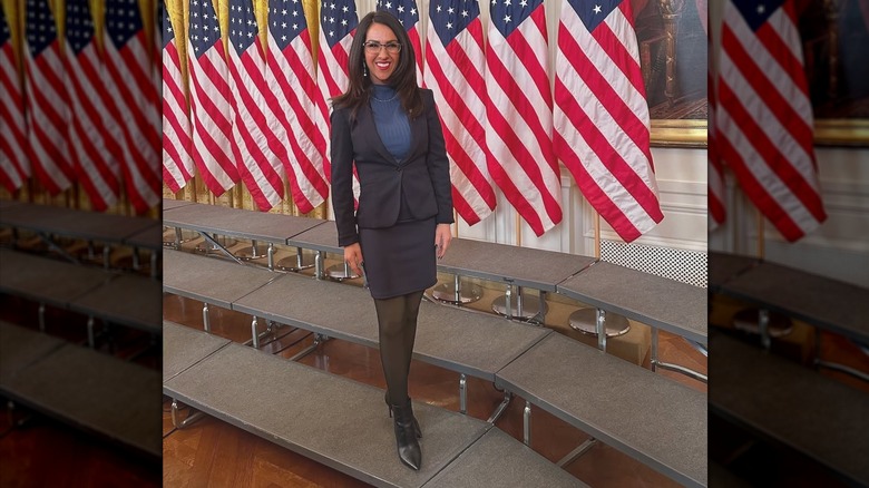 Congresswoman Lauren Boebert poses for a selfie in front of a line of flags