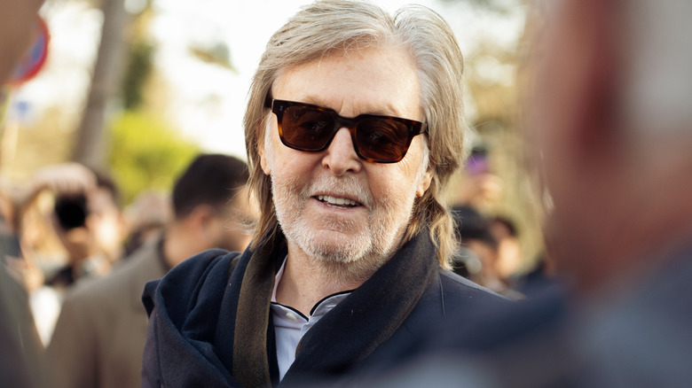 A smiling Paul McCartney wearing sunglasses