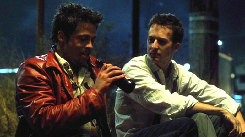 Tyler Durden, drinking a beer, and the Narrator sitting on the sidewalk in "Fight Club"